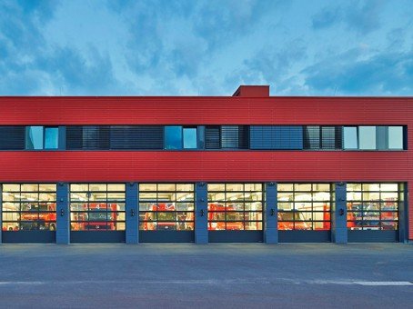 Gewerbehalle mit rot gestalteter Fassade und mehreren verglasten Sektionaltoren